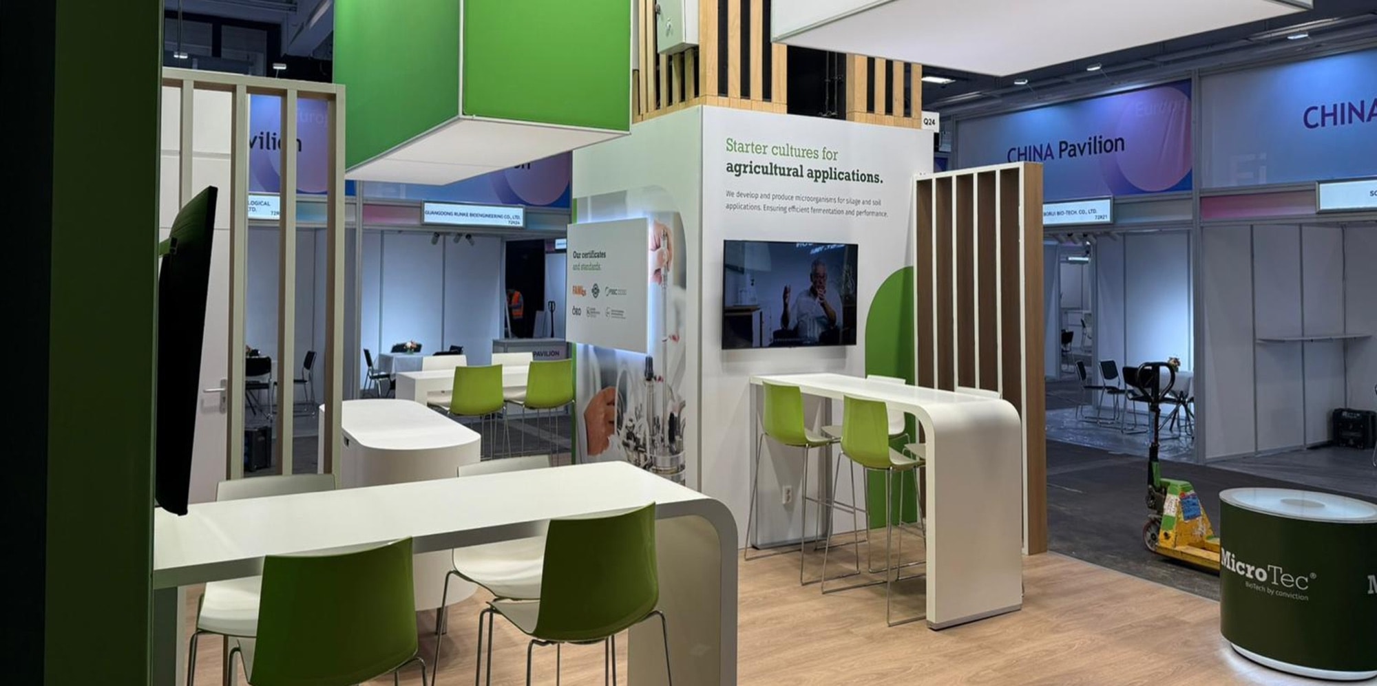 Messestand von MicroTec auf der FI Europe 2025 mit weißen Stehtischen, grünen Hockern und Wandgrafik zu Starterkulturen